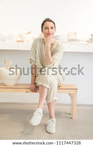 Woman in work wear in her workshop by table with handmade items