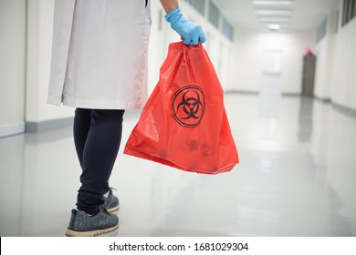 A Woman Worker Hand Holding Red Bag With Biohazard Sign In The Hospital.