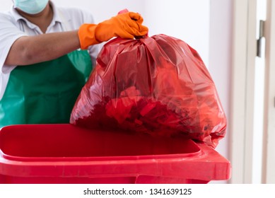 A Woman Worker Holding Red Garbage Bag Into Recycle Bin.Maid And Infection Waste Bin At The Indoor Public Building.Red Bin With Waste Bag On Floor In The Hospital.Infectious Control. 