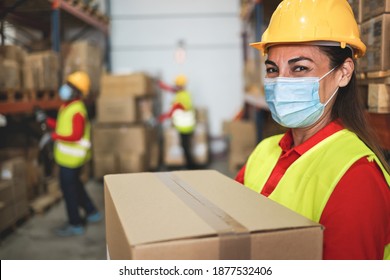 Woman worker inside warehouse loading delivery boxes while wearing safety mask for coronavirus prevention - Logistic and Industry concept - Soft focus on her eye