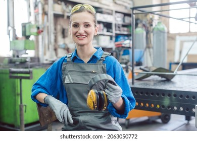Woman worker in metal factory showing protective workwear - Shutterstock ID 2063050772