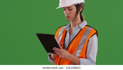 Woman worker in orange vest with tablet computer and hard hat on greenscreen - Powered by Shutterstock