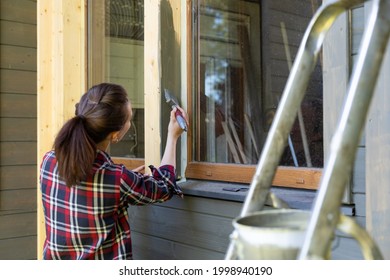 Woman Worker Painting Wooden House Exterior Wall With Paintbrush