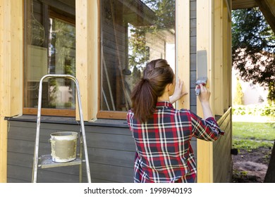 Woman Worker Painting Wooden House Exterior Wall With Paintbrush