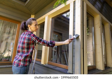 Woman Worker Painting Wooden House Exterior Wall With Paintbrush And Wood Protective Color Home Improvement Concept.