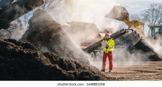 Woman Worker Standing With Clipboard In Industrial Compost Plant