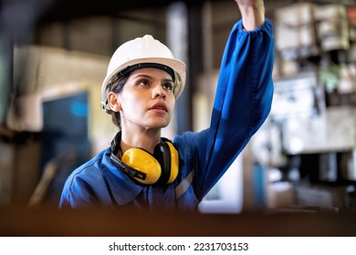 Woman worker in uniform operating machine at factory concentrate on fabrication job on drill - Powered by Shutterstock