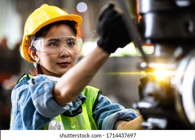 Woman worker wearing safety goggles control lathe machine to drill components. Metal lathe industrial manufacturing factory - Shutterstock ID 1714437697