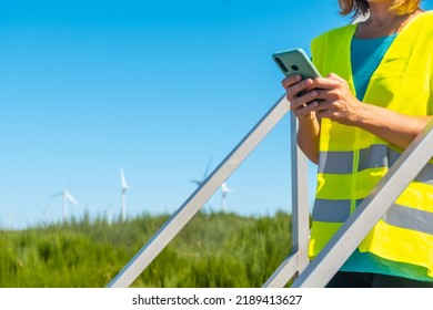 Woman Worker In A Wind Farm, Green Energy, Technical Review, With The Phone In Her Hand