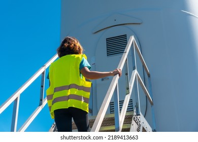 Woman Worker In A Wind Farm, Green Energy, Climbing The Stairs Of The Turbine