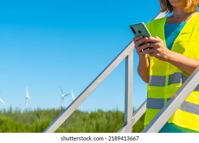 Woman Worker In A Wind Farm, Green Energy, Technical Review, With The Phone In Her Hand