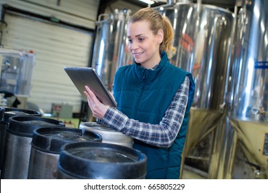 woman working at a brewery using a tablet - Powered by Shutterstock