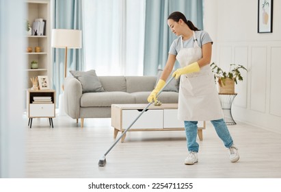 Woman working in a cleaning service mopping the living room floor of a modern home or apartment. Asian cleaner or housewife doing her job or housework to spring clean house for good hygiene lifestyle - Powered by Shutterstock