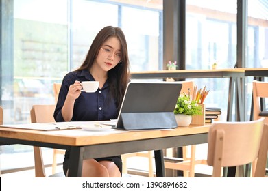 Woman working in co working space with coffee cup on hands. - Shutterstock ID 1390894682