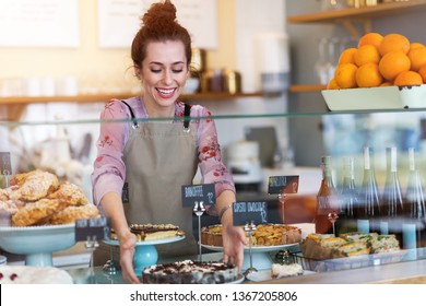 Woman working in coffee shop in Warsaw, Poland. Translation on black cards: „Banoffee Pie", „Fruit Cake”, „Apple Pie”, „Sandwiches” - Powered by Shutterstock