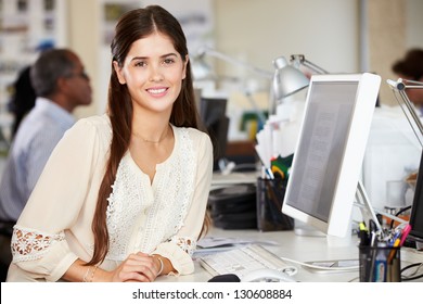 Woman Working At Desk In Busy Creative Office