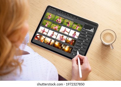 Woman working with digital photo files library and editing photos on tablet computer