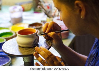 Woman working In her pottery studio. Ceramic workshop. Paint on clay cup in the pottery. Painting in pottery - Powered by Shutterstock