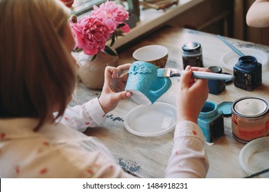 Woman working In her pottery studio. Ceramic workshop. Paint on clay cup in the pottery. Painting in pottery - Powered by Shutterstock