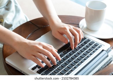 Woman working at home, with hand on keyboard. Young woman working on computer at table in hotelroom. Hands of an office woman typing. Woman using laptop.