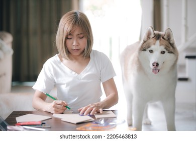 A Woman Working At Home With Her Dog.