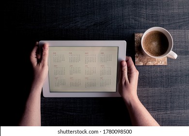 Woman working at home with a tablet and a cup of coffee on a grey wood table