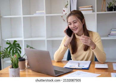 Woman working from home using laptop computer while reading text message on mobile phone