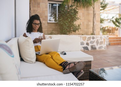 Woman Working From Home At The Yard On Her Computer And Typing On The Mobile Phone