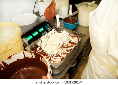 Woman Working At Ice Cream Factory Is Decorations Of Creamy Vanilla Ice Cream With Chocolate Dressing In Steel Container. Pouring Chocolate In The Tray With Frozen Ice Cream. Beautiful Dessert, Sweet.