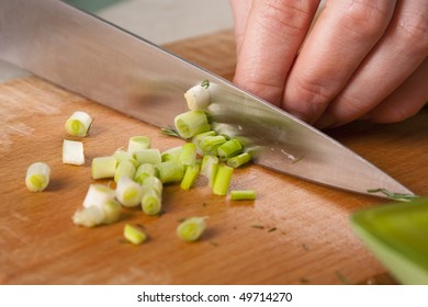 Woman Working In The Kitchen Chopping Up The Vegetables. Female Slicing Spring Onions For Salad. Close Up Chef Cutting Onions.