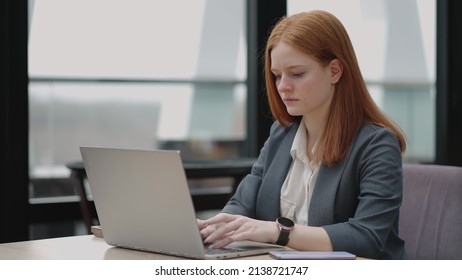 Woman Is Working With Laptop In Office, Typing E-mail For Partners And Employees, Serious And Successful Businesswoman