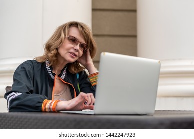 Woman working at a laptop in a summer outdoor cafe - Shutterstock ID 1442247923