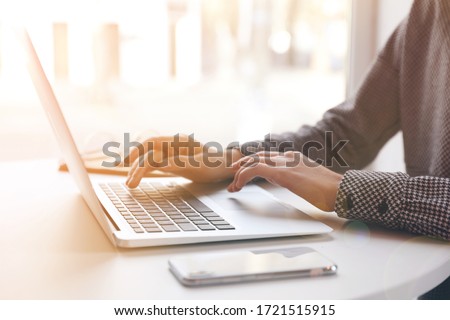 Woman working with laptop at table indoors, closeup