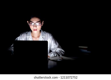 Woman Working Late At Her Home Office. Beautiful Asian Woman Working On Her Computer, Full Concentration, Wearing Glasses. Modern Global Connected Business Concept.