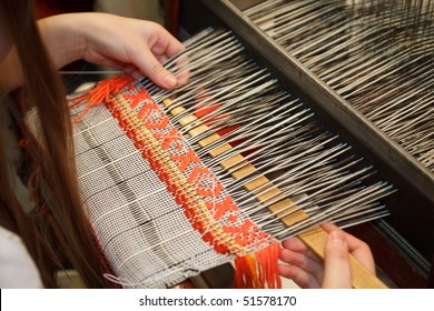 Woman working at the loom. Russian national crafts. Focus on the fabric.