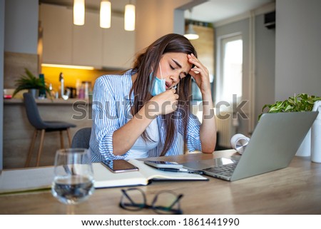 Woman working in the office and having difficulties breathing with face mask, she is pulling the mask down. The woman had to remove the mask to breathe after having to wear it for a long time