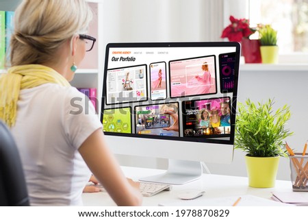 Woman working in office and viewing sample creative agency's website on computer screen