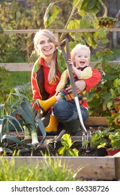 Woman Working On Allotment With Child