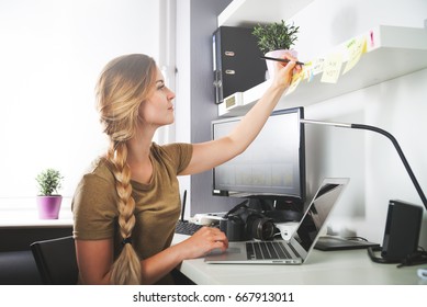 Woman working on computer at home office taking memo note