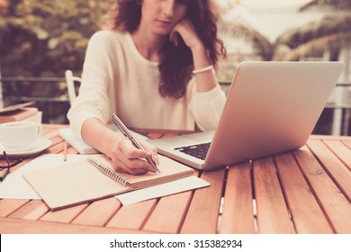 Woman working on computer and writing down her thoughts