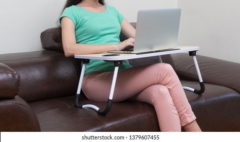 Woman Working On Laptop Computer On Portable Table At Home