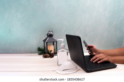 Woman Working On Laptop Computer In Office Or Store At Christmas During Coronavirus Time With Face Mask And Hand Sanitizer. 