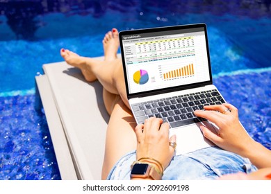 Woman working on laptop computer while relaxing by the pool outdoors