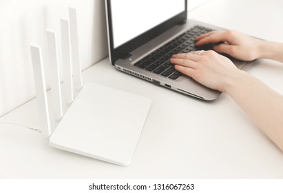 Woman Working On A Laptop At Home. White Wifi Router On White Background. Minimalism