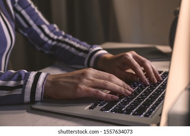 Woman working on laptop at table in evening