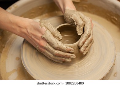 Woman working on the potter's wheel. Artisan making a cup from clay pot. Workshop of handmade modeling on the potters wheel. - Powered by Shutterstock