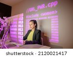 Woman working on programming code with girl power projection and pink digital code.