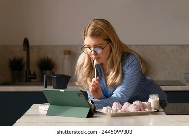 Woman working on tablet in kitchen with breakfast. Distant work. Girl freelancer - Powered by Shutterstock