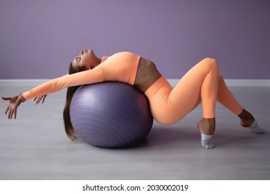 Woman working out with exercise ball in the gym. Pilates woman doing exercises in the gym with a fitness ball. Fitness woman doing abdominal exercises with ball
