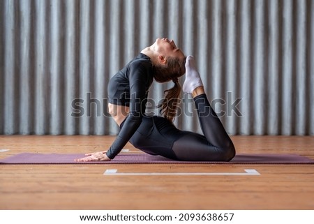 Woman working out at home, arching her back and reaching her toes for her head.